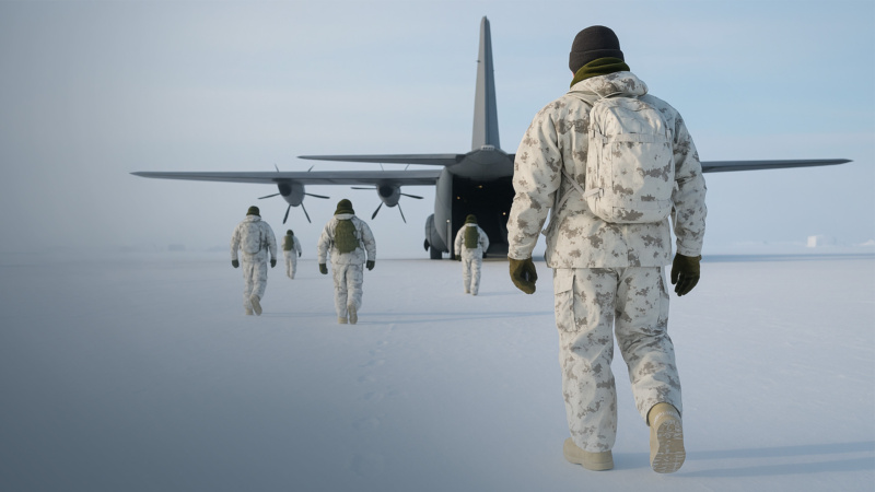 Soldiers in white winter camouflage walk across a snowy landscape toward the open rear ramp of a large military transport aircraft, leaving footprints behind them in the frozen ground.