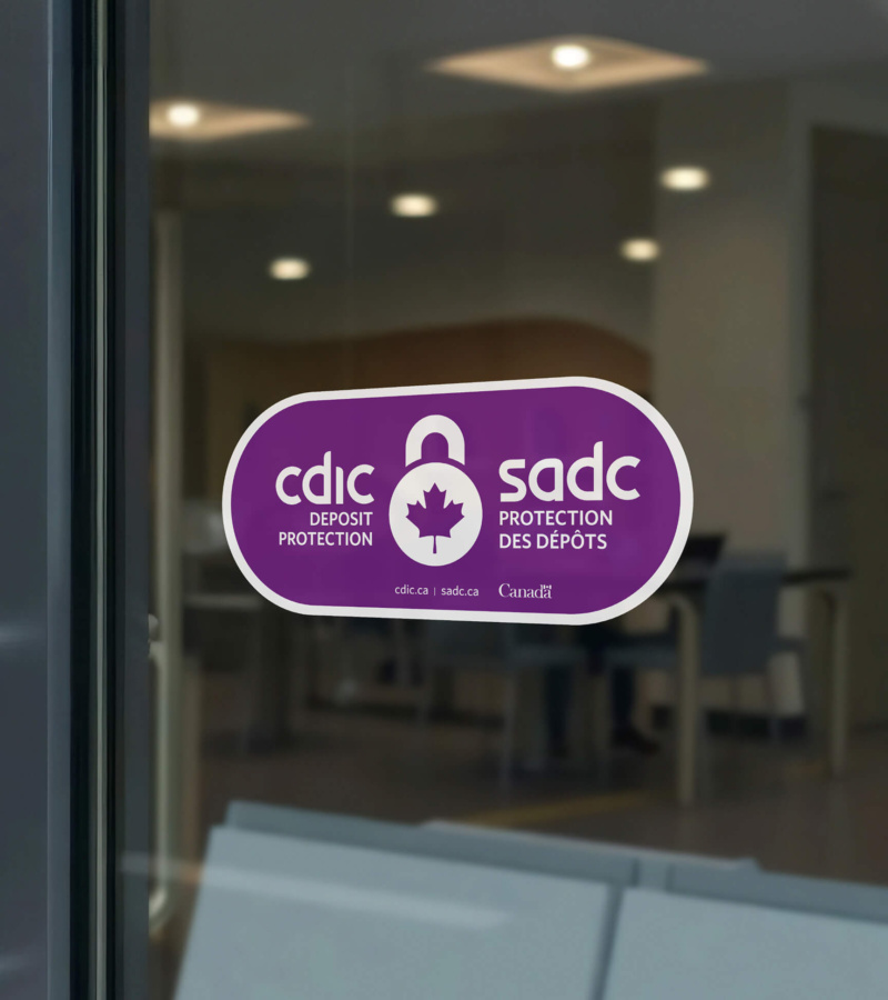 Purple CDIC deposit protection decal on a glass door, with a blurred office interior visible in the background.