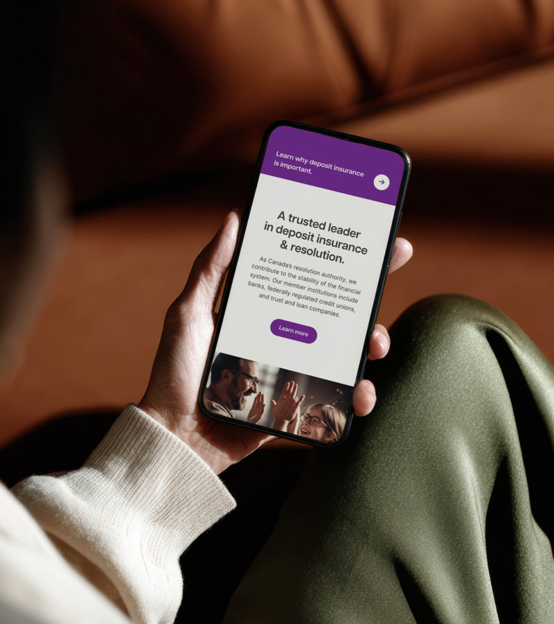 “Hand holding a smartphone displaying the CDIC mobile website, showing a page about deposit insurance and resolution.
