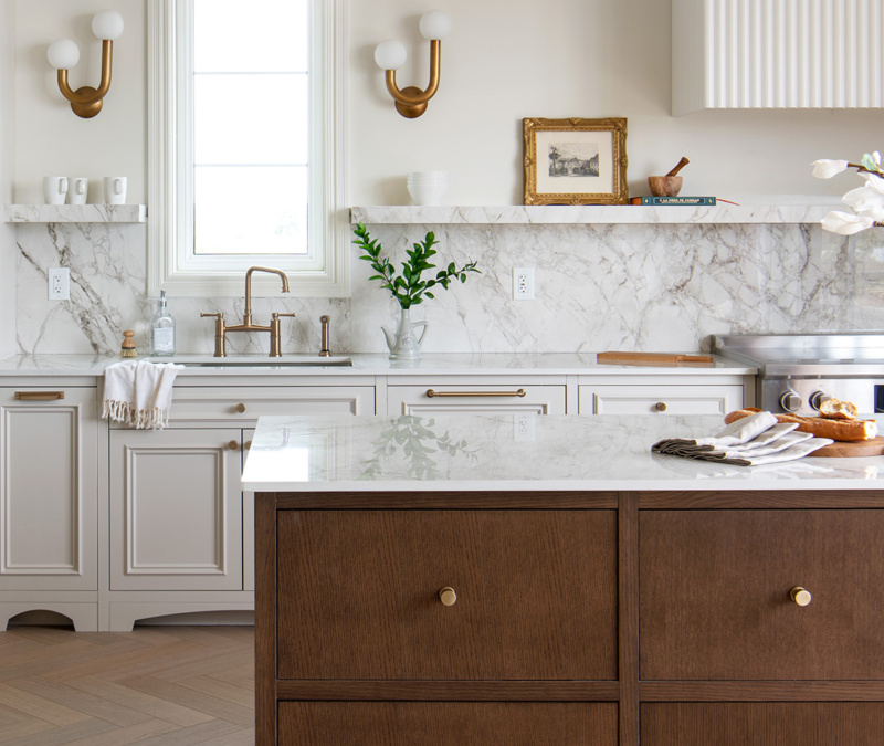 Modern kitchen with marble backsplash, gold fixtures, and wood island.