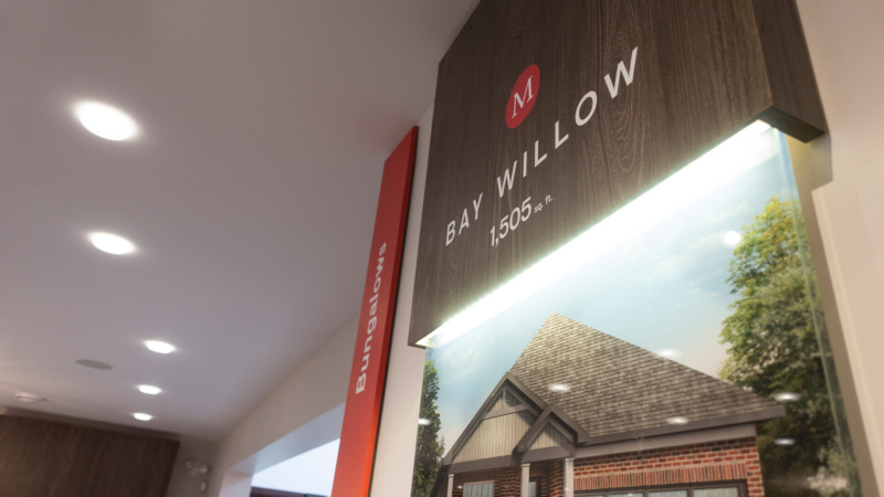 Interior detail of a Mahogany sales centre display featuring the Bay Willow home model signage and illuminated wall graphics.