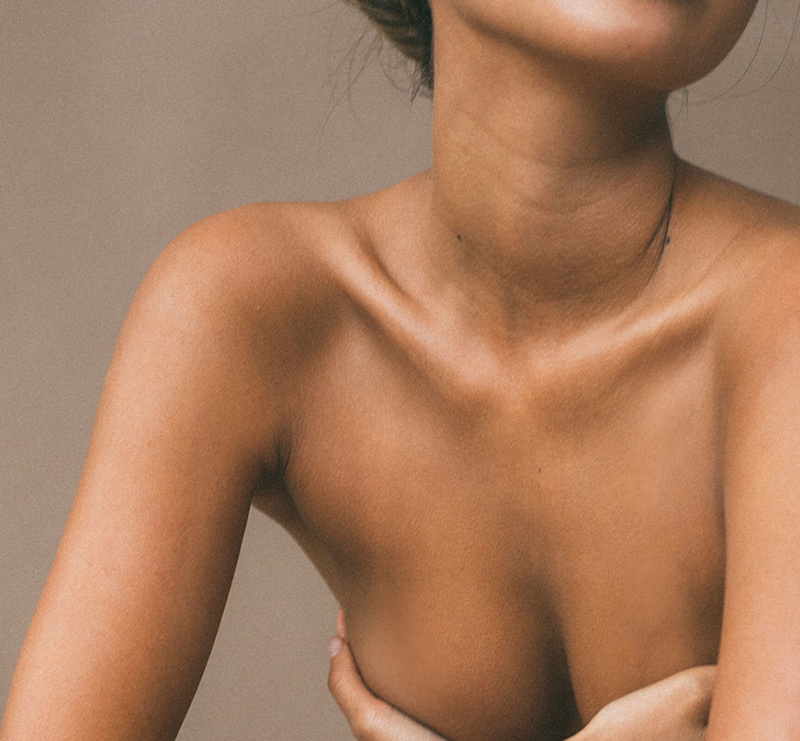 Close-up of a woman’s neck, shoulders and collarbone against a neutral background