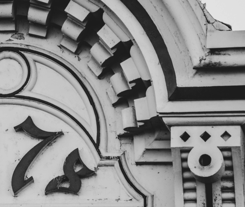 Close-up of historic building details with the number “1878” in black-and-white, showing ornate stonework and weathered texture.Text on a burgundy background reading, “It’s surprising how connected you are here.”