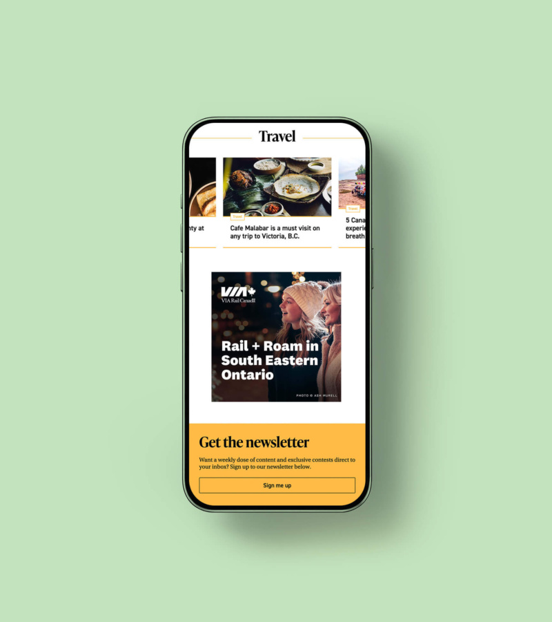 Smartphone displaying a VIA Rail digital ad titled “Rail + Roam in South Eastern Ontario,” featuring a mother and daughter shopping outdoors in a snowy scene.