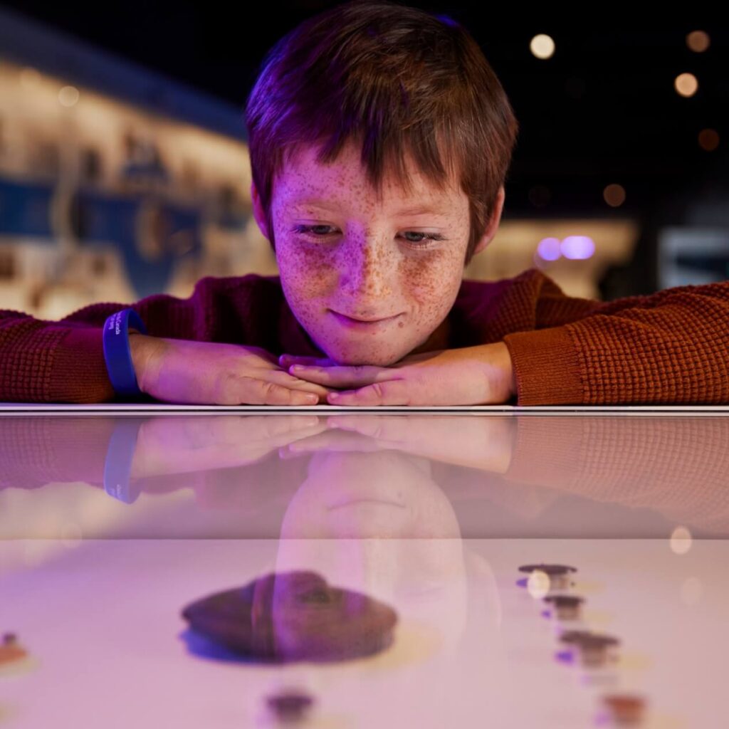little boy looking on on at the bank of Canada museum artifact with wonder